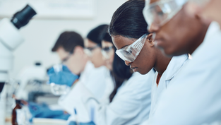 Students in lab coats and safety glasses conducting an experiment—representing LAPU’s bachelor of science health sciences program and hands-on learning in healthcare education.