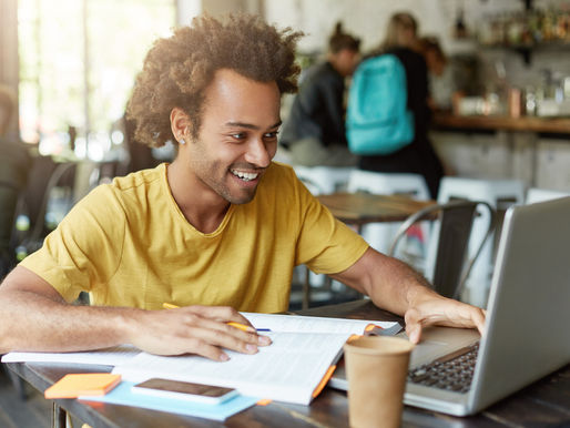 A student working on a laptop in a study area, symbolizing the flexibility and versatility of an online Associate of Arts in Humanities program.
