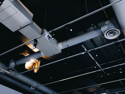 Exposed commercial HVAC ductwork and ventilation system in a building ceiling, illustrating commercial indoor air quality management and airflow distribution.