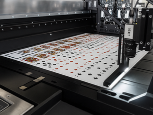 A variety of custom card decks being printed by a card manufacturer on a professional printing press.