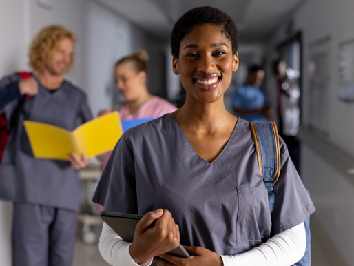 Smiling public health student in scrubs holding a tablet in a hospital hallway, representing future MPH career opportunities in healthcare leadership and education.