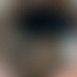 Rusty circular frame views an empty cave with a dirt floor, scattered equipment, and blue pallets. The setting feels abandoned and eerie.