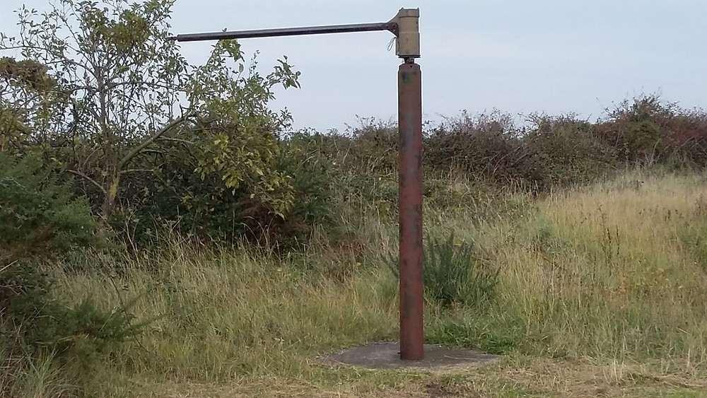 A post which helped launch dummy planes stands proud of the marshland at Stiffkey