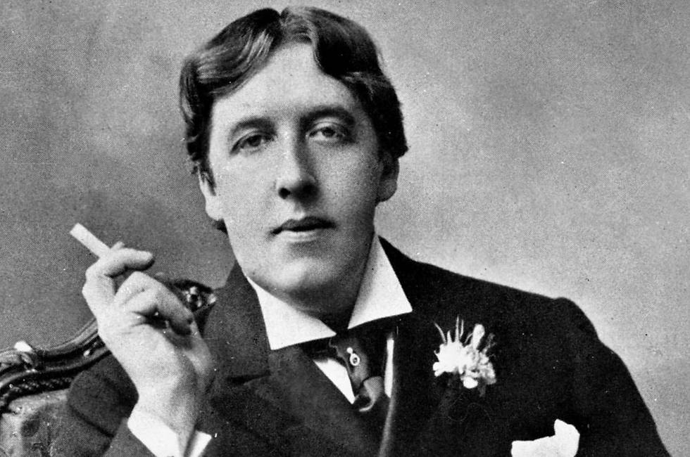 Oscar Wilde known for his biting wit sits with a cigarette in his hand