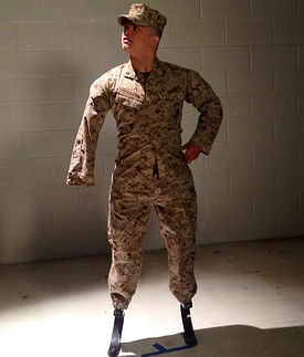 A triple amputee marine posing in front of a block wall