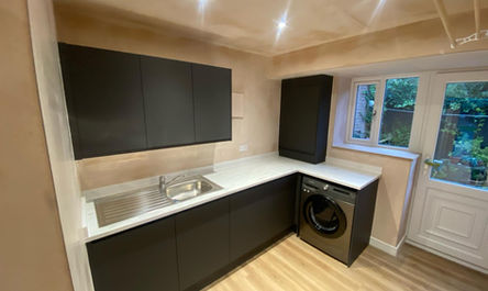 Modern kitchen interior, a product of garage conversion gurus, with dark cabinets, stainless steel sink, and integrated appliances.