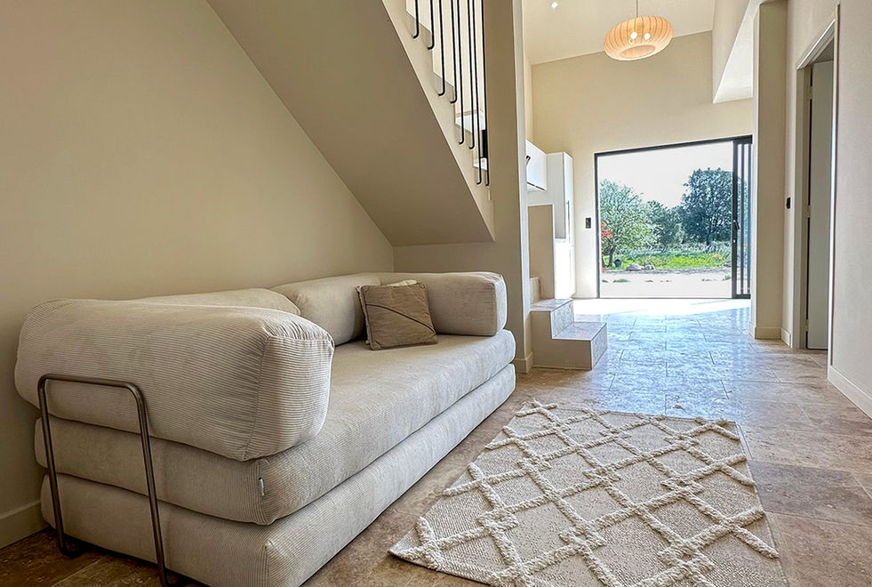 Séjour épuré avec canapé beige, tapis berbère et baie vitrée ouverte sur le jardin ensoleillé, villa Solenzara Corse