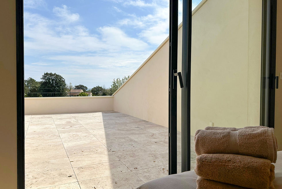 Vue depuis la chambre sur terrasse privative en travertin et paysage arboré, villa Palauma Solenzara Corse