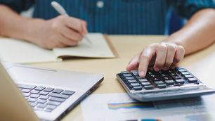 Person working on medical billing tasks using a laptop, noting payment details on paper. Represents accurate payment posting and financial data review in healthcare or medical billing processes.