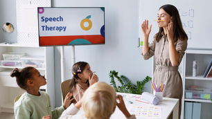 A speech therapist works with a group of young children in a classroom setting, practicing speech exercises