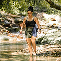 Picture of Kate in a forest setting at a Retreat walking through a river