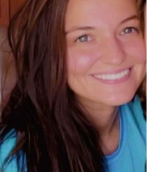 Smiling woman with long brown hair wearing a blue top.
