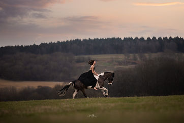 a girl galloping with her horse in a moody setting across the british countryside