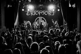 Konzertpublikum vor Bühne mit Band und erhobenen Händen