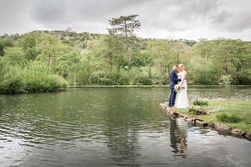 bride and groom have a landscape photo alongside a large pond 