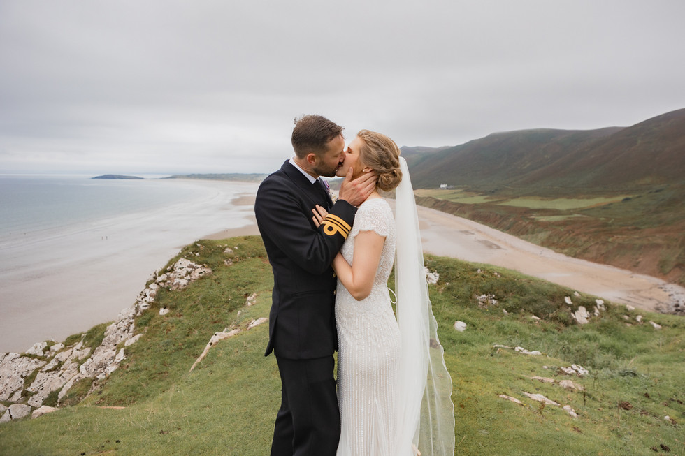 Bride and groom pose for couples wedding photography at Rhossili bay in the Gower