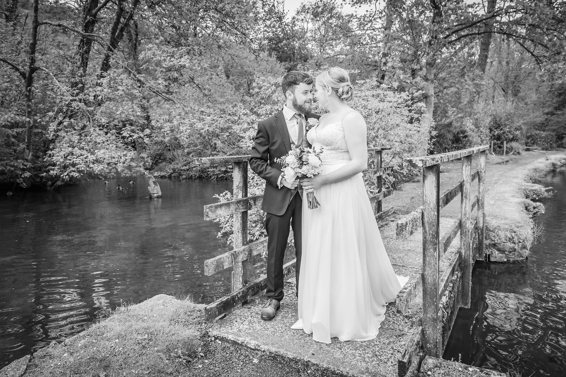 bride and groom enjoy their photoshoot on a bridge in a swansea park