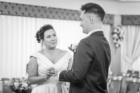 bride pushes on wedding ring onto grooms finger