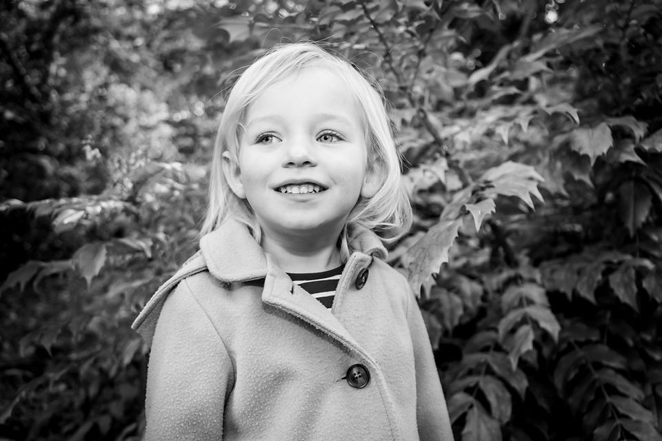 girl smiles in clyne gardens by bushes at the photographer 