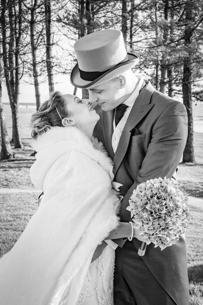 a happy bride and groom embrace each other on Swansea Bay
