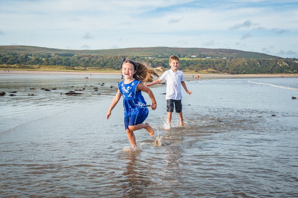 siblings play in the surf on a gower beach photo shoot