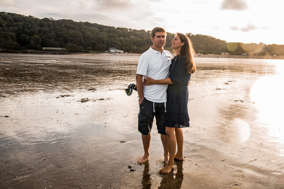 husband and wife embrace in the sunset at oxwich bay