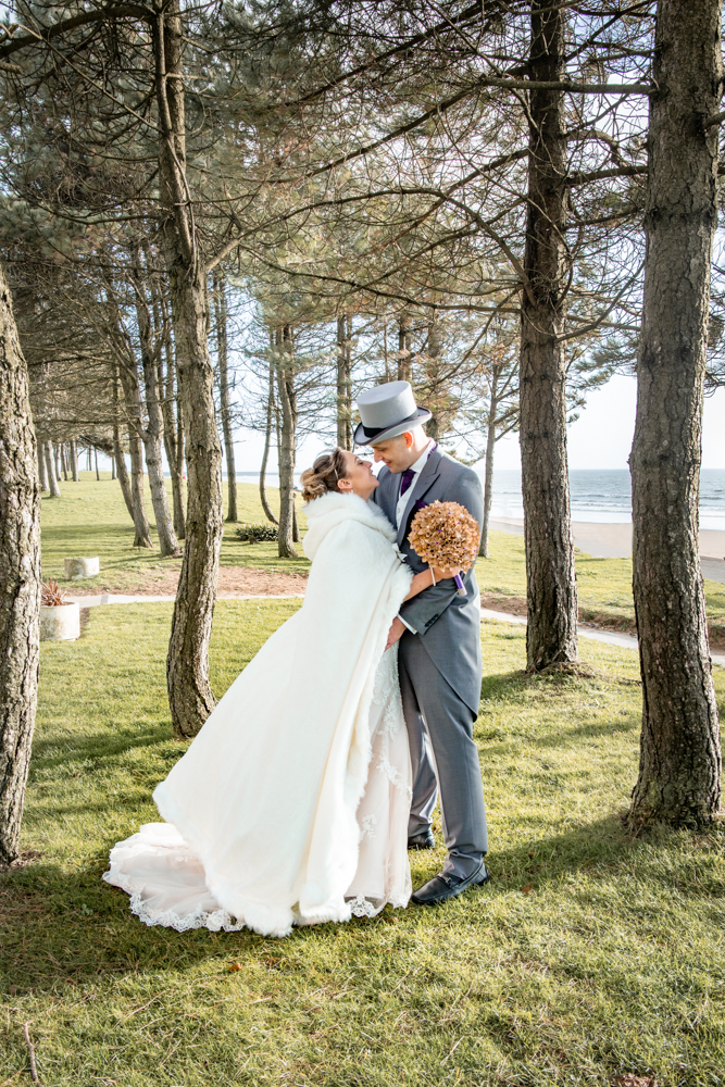 Bride and groom pose in Swansea trees at Swansea Bay