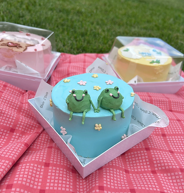 A blue bento cake featuring cute piped green frogs.