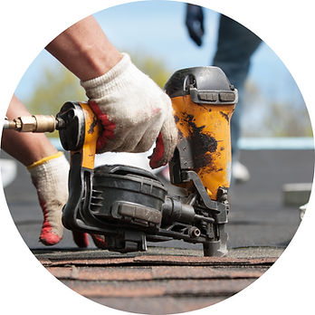 Roofer using a pneumatic nail gun to fasten asphalt shingles on a Kansas roof