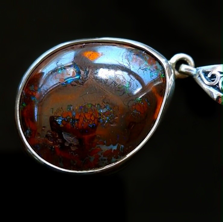 Handcrafted sterling silver necklace featuring a freeform polished Queensland boulder opal stone. left view