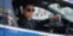 Homem elegante dirigindo carro de luxo em ambiente urbano.
