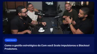 Quatro homens conversam em um estúdio de podcast moderno com microfones e xícaras de café sobre a mesa, representando o case de sucesso da parceria entre a Com você Scala e a Blackout Produtora.