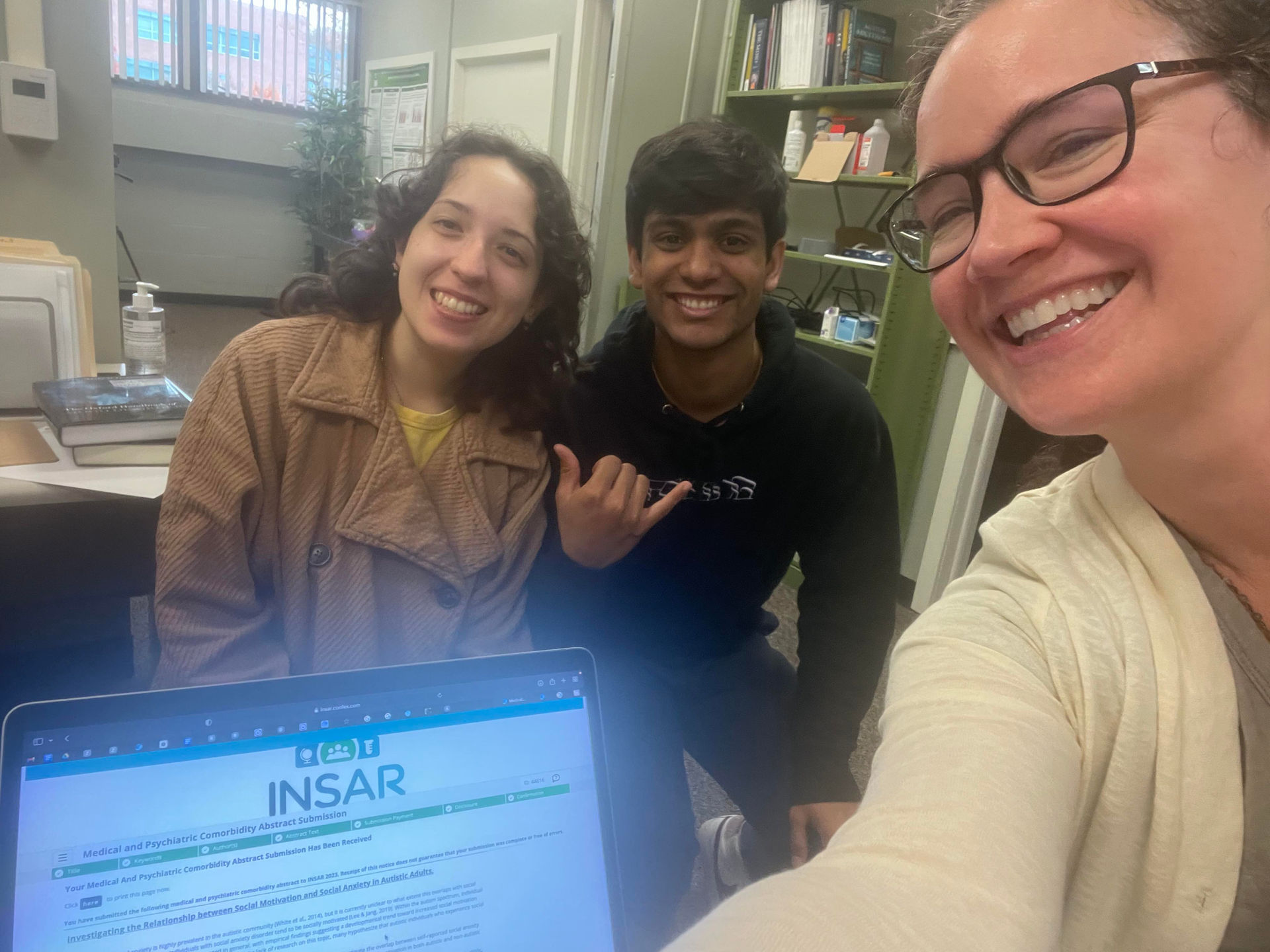 Photo of Claudia, Elisha, and Kaite smiling with the INSAR submission page.