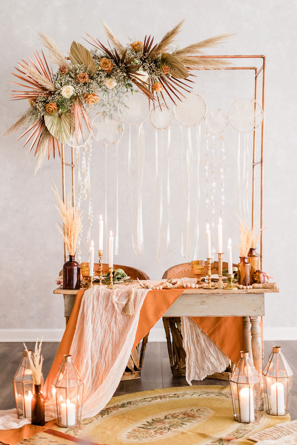 sweetheart table with rust linens, amber bottles filled with pampas grass
