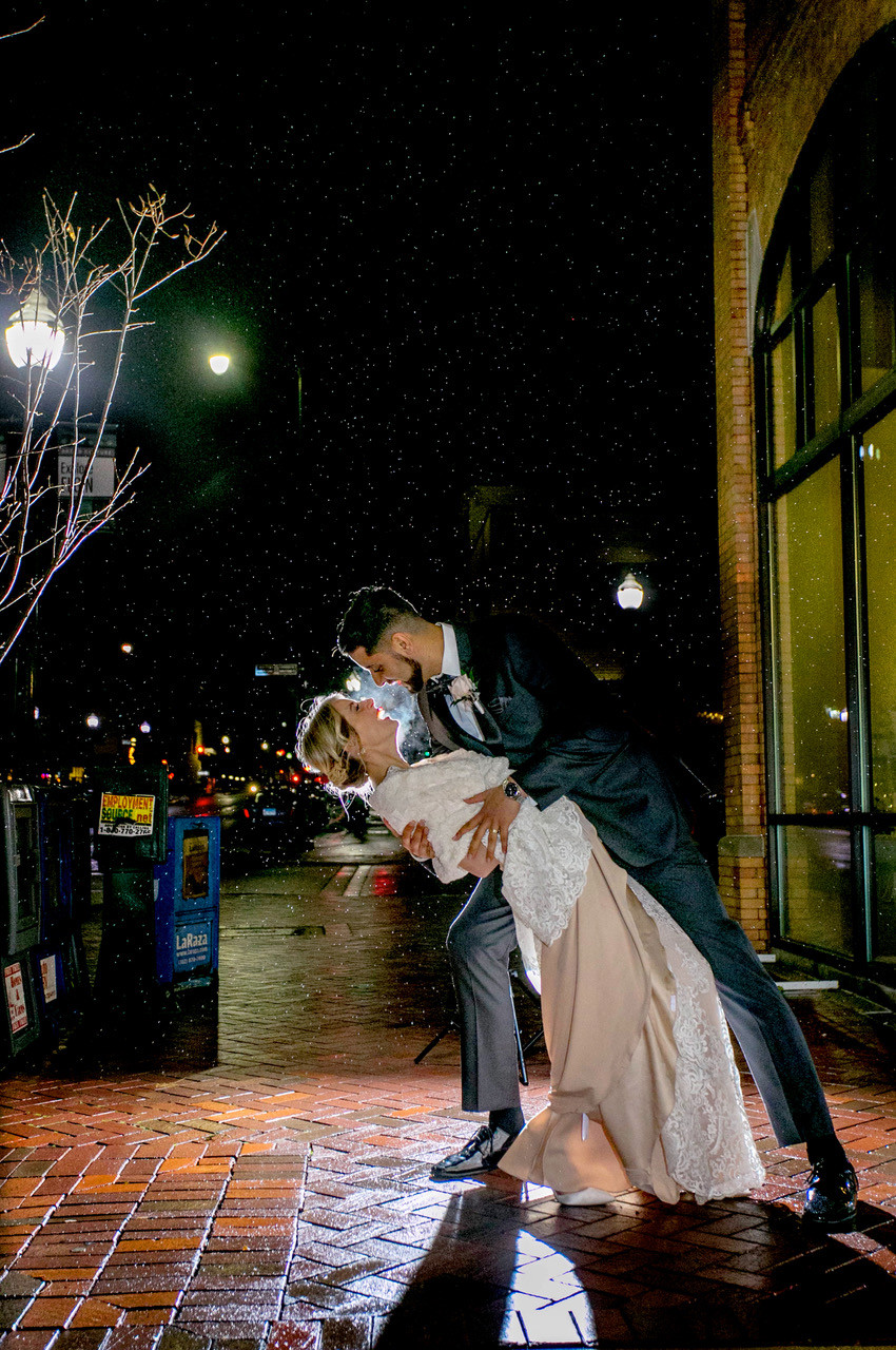 Couple share a kiss outside their reception venue in Elgin, IL after tiny wedding