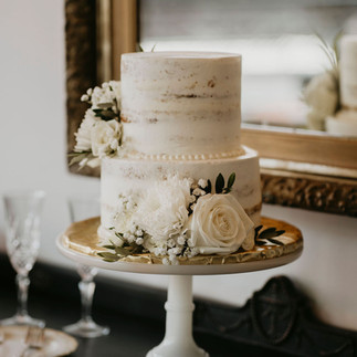 two tier naked cake decorated with fresh floral on pedestal cake stand