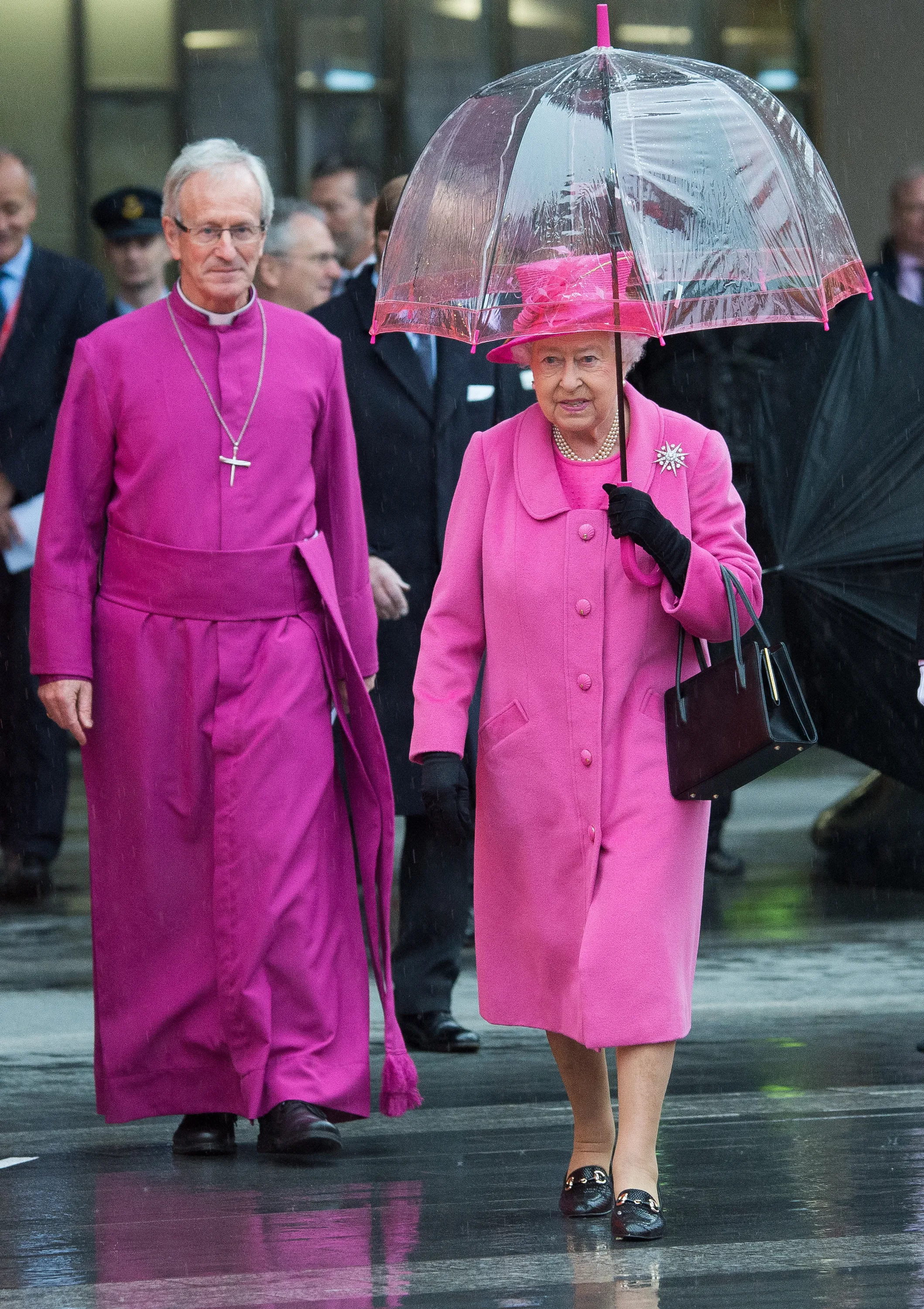 The Queen wears a bright cerise pink dress and coat with a pink-tipped umbrella whilst visiting Birmingham in 2015