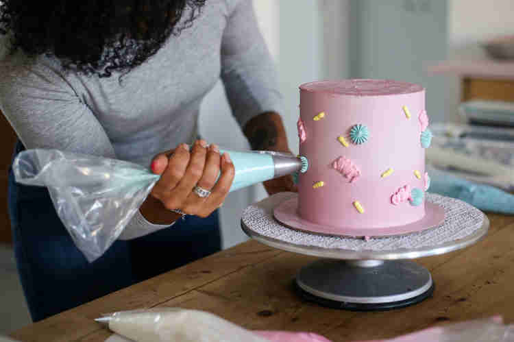 Oleh Lee'at Gentely decorating a pink cake with frosting