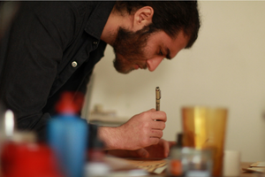 Peter Shamah holding a pen and studying his artwork