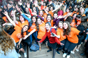 Orly Wahba posing with a crowd of smiling young women with raised arms