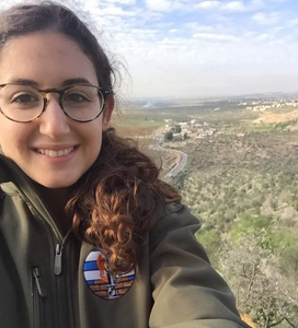 A selfie of Olah Chantelle Leiderman in her IDF uniform with hills behind her