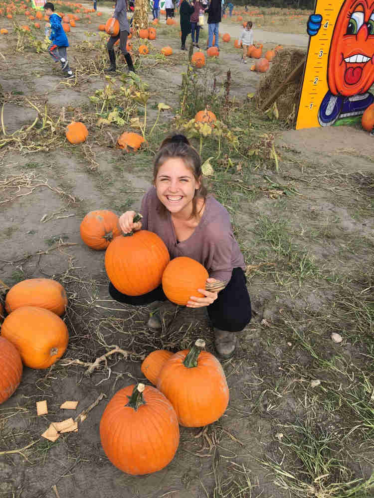 Oleh Kayla Rosen picking pumpkins in a pumpkin patch