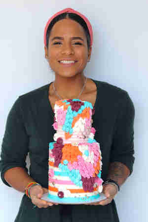 Oleh Lee'at Gentely holding up a colorful cake she decorated