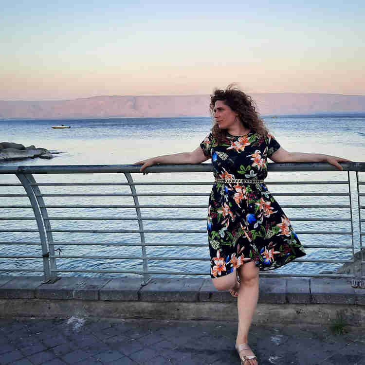 Raizel Druxman leaning her back against a metal fence over a body of water