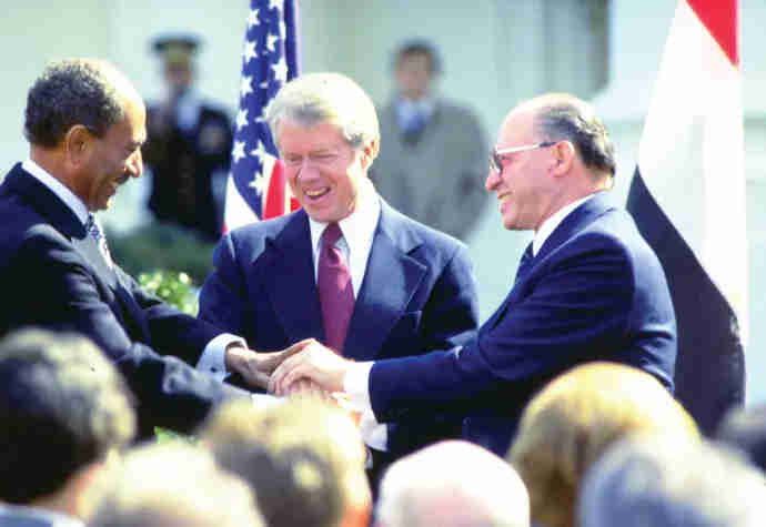 Prime Minister Menahem Begin, President Carter, and President Anwar Sadat shaking hands after signing the Egypt / Israel Peace Treaty