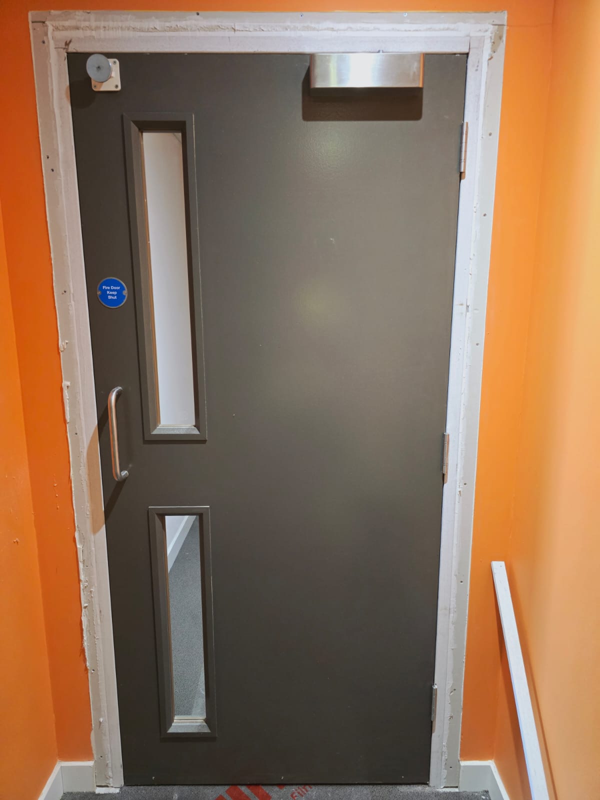 Glazed communal door during frame works, Barlett Park