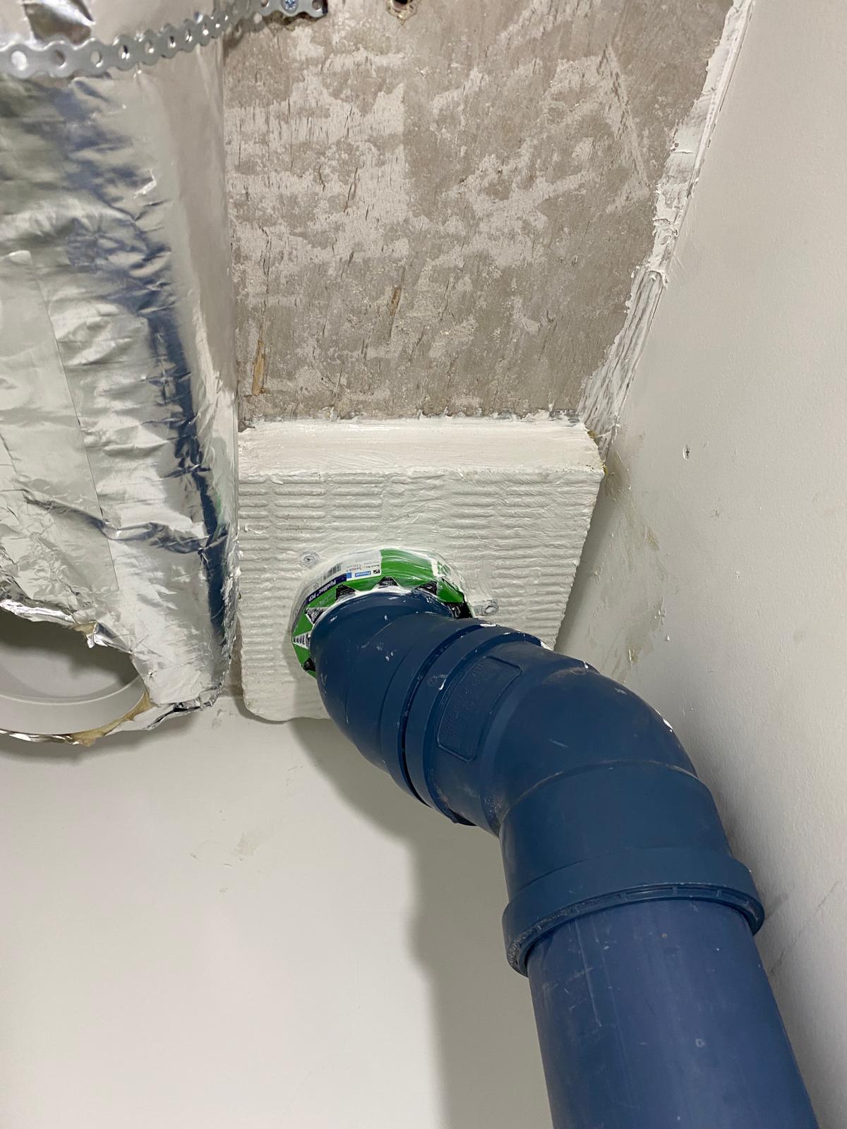 Pipe collar and batt detail beside an insulated duct, Cobham firestopping project