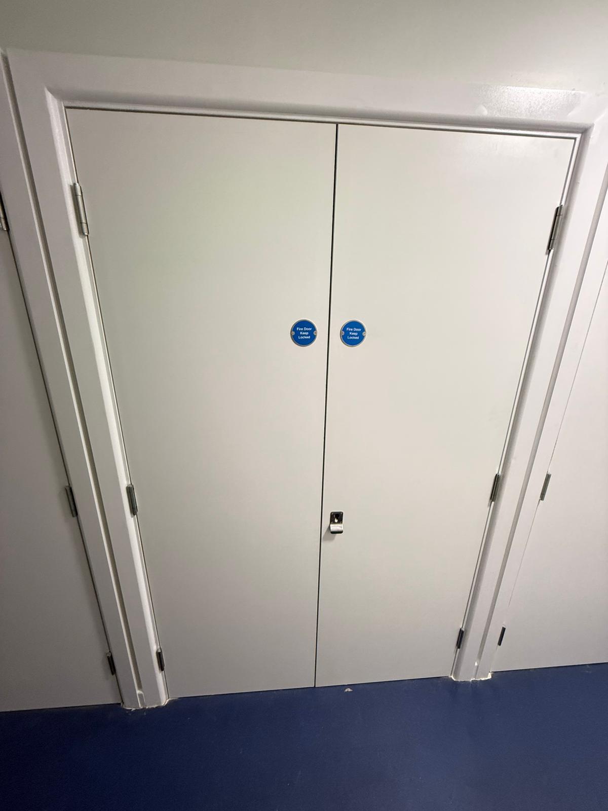 Paired service-cupboard doors with fire-door signage, Burlington Court