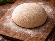 Pizzateigling liegt auf einem Holzbrett