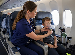 SkyCare Global medical escort onboard commercial aircraft with solo child traveler assisting with inflight oxygen with care